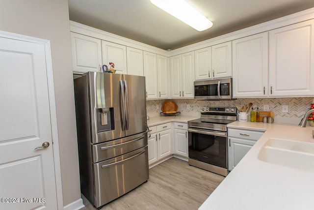 kitchen featuring light hardwood / wood-style floors, sink, tasteful backsplash, white cabinetry, and appliances with stainless steel finishes