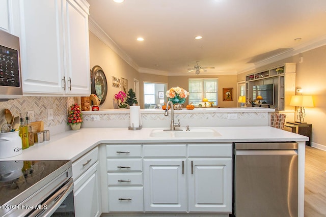 kitchen with stainless steel appliances, white cabinetry, sink, kitchen peninsula, and ornamental molding