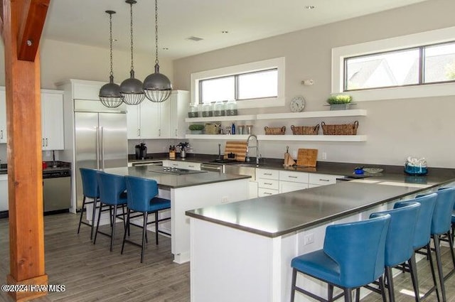 kitchen featuring dark hardwood / wood-style flooring, decorative light fixtures, white cabinets, a center island, and a breakfast bar area