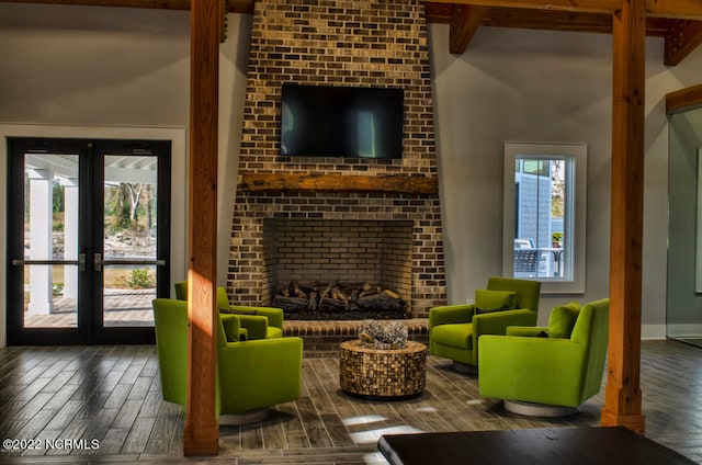 living room with french doors, a fireplace, wood-type flooring, beamed ceiling, and a high ceiling