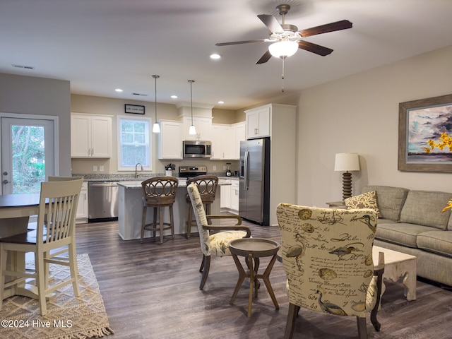 living room featuring ceiling fan, sink, and dark wood-type flooring