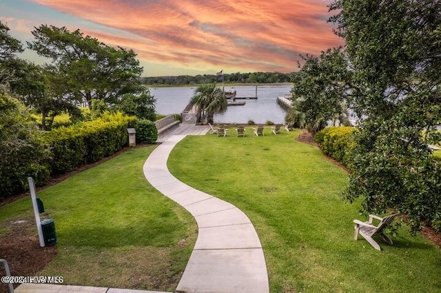 view of property's community featuring a water view, a yard, and a dock