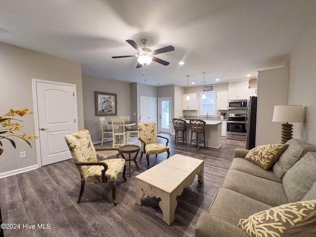 living room featuring ceiling fan and dark hardwood / wood-style flooring