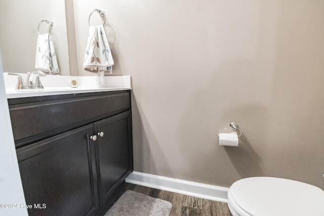 bathroom with wood-type flooring, vanity, and toilet