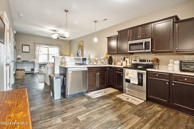 kitchen featuring dark brown cabinetry, appliances with stainless steel finishes, ceiling fan, hanging light fixtures, and dark hardwood / wood-style flooring