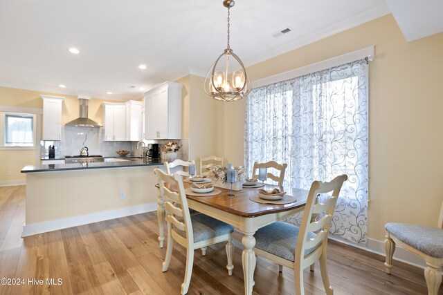 dining room featuring crown molding, sink, a chandelier, and light wood-type flooring