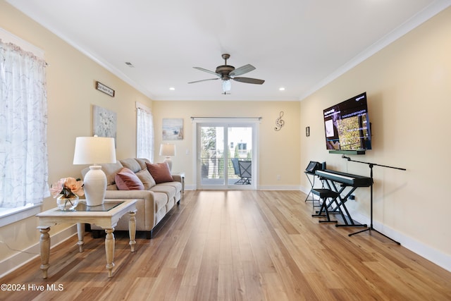 living room featuring ceiling fan, light wood-type flooring, and crown molding