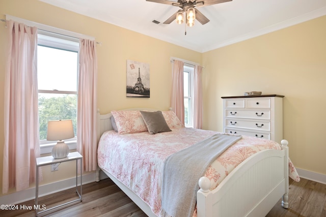 bedroom with crown molding, ceiling fan, and dark wood-type flooring