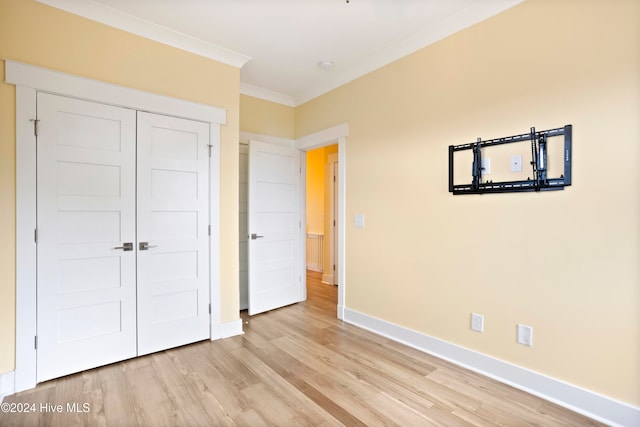 unfurnished bedroom featuring crown molding, a closet, and light wood-type flooring