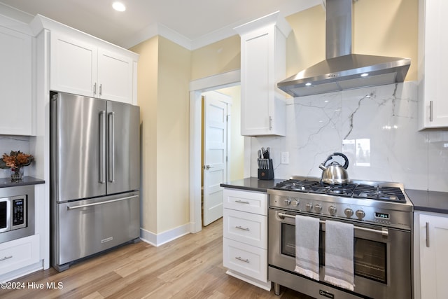 kitchen with light hardwood / wood-style flooring, white cabinets, wall chimney range hood, and high end appliances