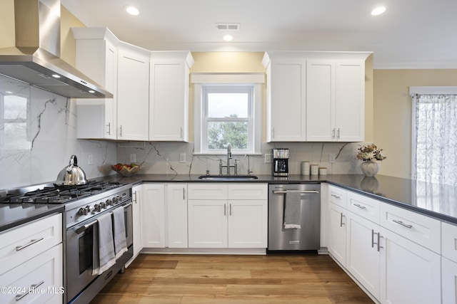 304 Birmingham Ave Unit 2, Carolina Beach, NC 28428 - kitchen with wall chimney exhaust hood, stainless steel appliances, a sink, dark countertops, and white cabinetry