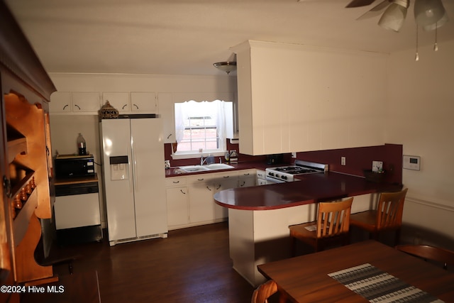 kitchen with kitchen peninsula, white appliances, dark wood-type flooring, sink, and white cabinets