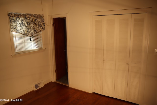 unfurnished bedroom with a closet and dark hardwood / wood-style floors