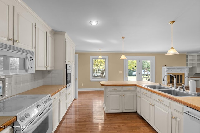 kitchen with white cabinetry, appliances with stainless steel finishes, decorative light fixtures, and light hardwood / wood-style flooring