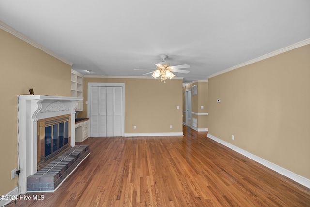 unfurnished living room with ceiling fan, wood-type flooring, crown molding, and a brick fireplace