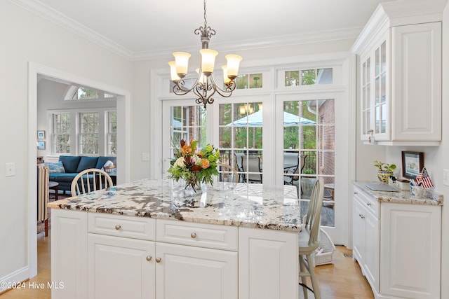 kitchen with a center island, an inviting chandelier, crown molding, light hardwood / wood-style flooring, and white cabinetry