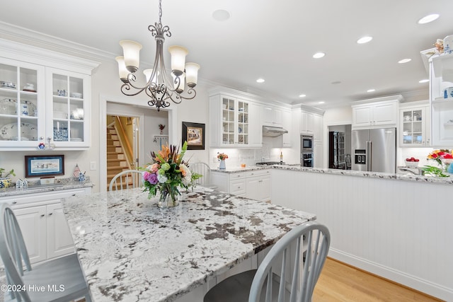 dining space with crown molding, light hardwood / wood-style floors, and an inviting chandelier