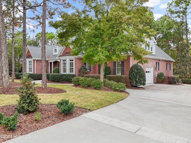 new england style home with a front yard and a garage