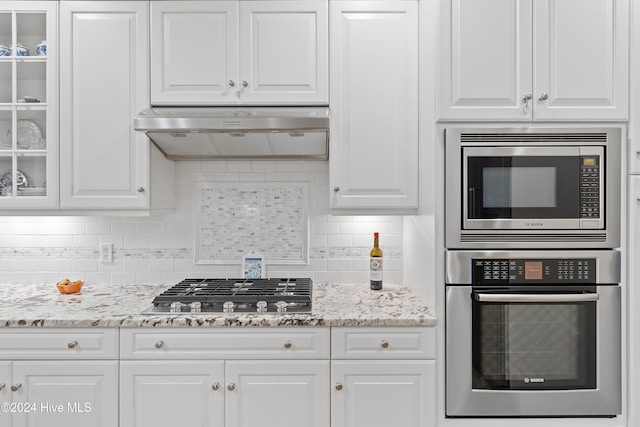 kitchen featuring white cabinets, stainless steel appliances, exhaust hood, and tasteful backsplash