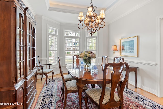 dining room featuring hardwood / wood-style flooring, an inviting chandelier, a tray ceiling, and crown molding