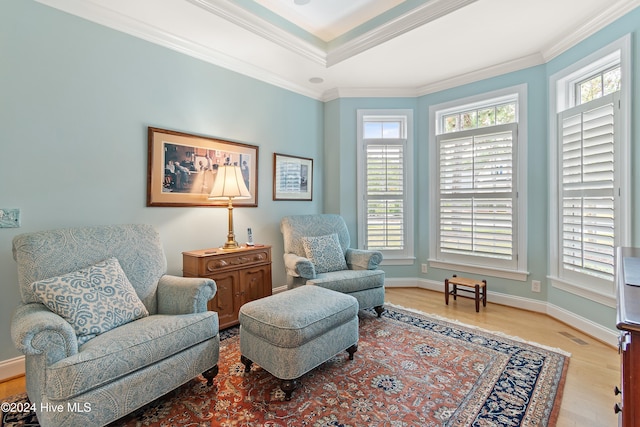 living area with light hardwood / wood-style floors and ornamental molding