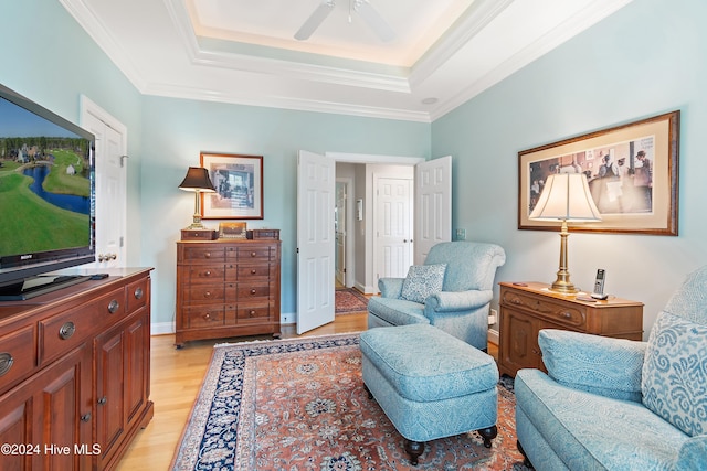 sitting room with a tray ceiling, light hardwood / wood-style flooring, ceiling fan, and ornamental molding