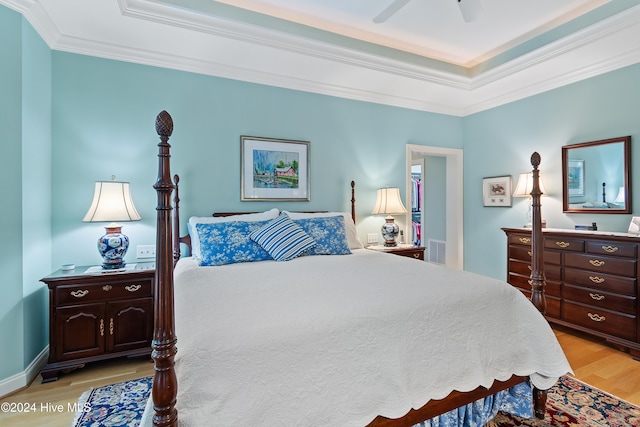 bedroom with a tray ceiling, ceiling fan, light hardwood / wood-style floors, and ornamental molding