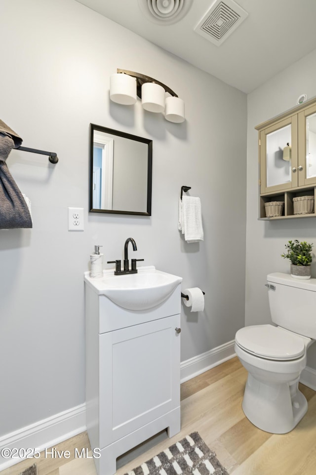 bathroom with toilet, vanity, and hardwood / wood-style flooring