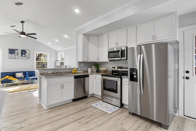 kitchen featuring sink, kitchen peninsula, vaulted ceiling, white cabinets, and appliances with stainless steel finishes