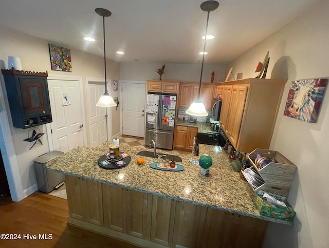 kitchen featuring sink, hanging light fixtures, light hardwood / wood-style flooring, kitchen peninsula, and stainless steel fridge