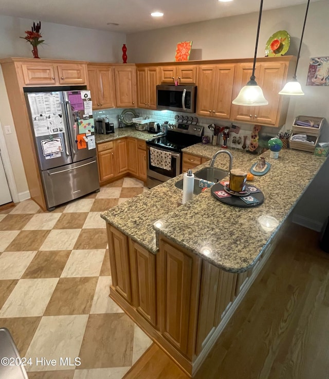 kitchen with kitchen peninsula, light stone countertops, stainless steel appliances, sink, and pendant lighting