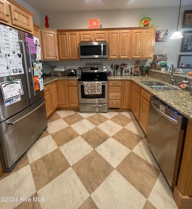 kitchen featuring tasteful backsplash, light stone counters, stainless steel appliances, sink, and decorative light fixtures