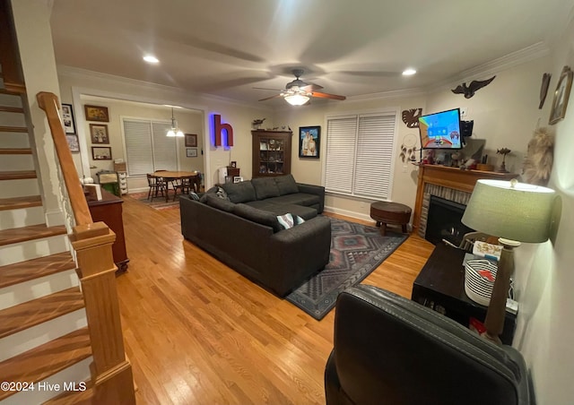 living room featuring a fireplace, ceiling fan, light hardwood / wood-style flooring, and ornamental molding