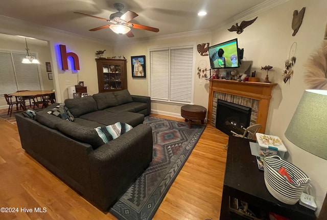 living room featuring ceiling fan, hardwood / wood-style floors, crown molding, and a brick fireplace