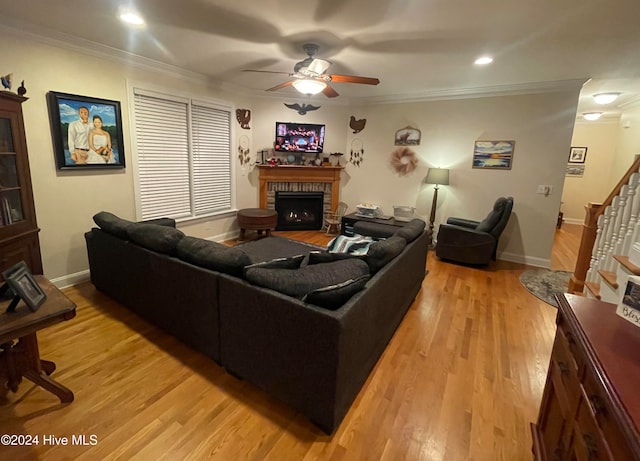 living room with a fireplace, ornamental molding, ceiling fan, and wood-type flooring