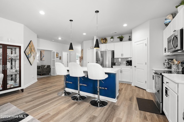 kitchen featuring pendant lighting, a center island, appliances with stainless steel finishes, light hardwood / wood-style floors, and white cabinetry