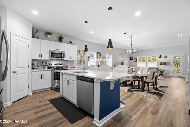 kitchen with wood-type flooring, white cabinetry, a kitchen island with sink, and appliances with stainless steel finishes