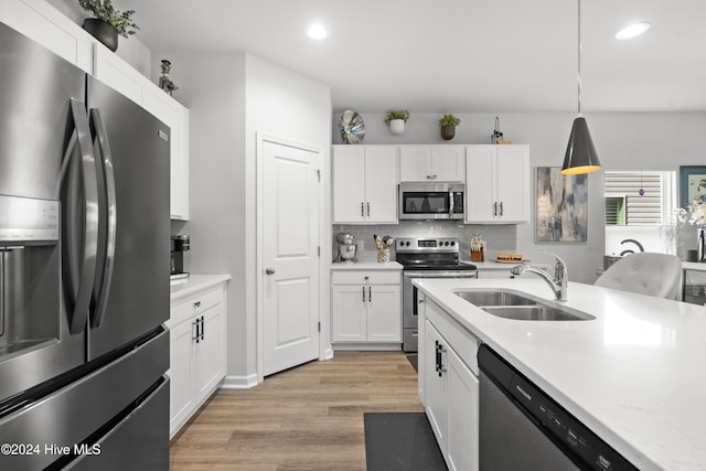 kitchen with appliances with stainless steel finishes, white cabinetry, hanging light fixtures, and sink