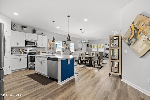 kitchen featuring plenty of natural light, an island with sink, pendant lighting, and appliances with stainless steel finishes