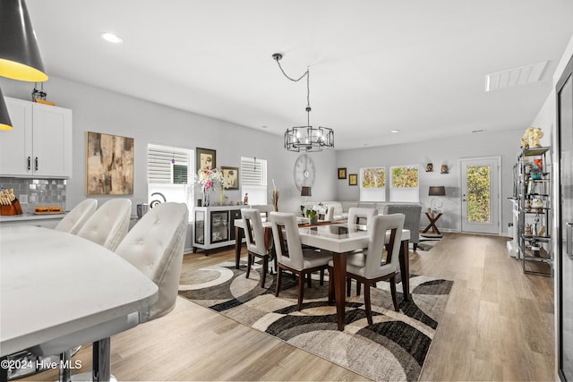 dining room with light hardwood / wood-style flooring and a chandelier