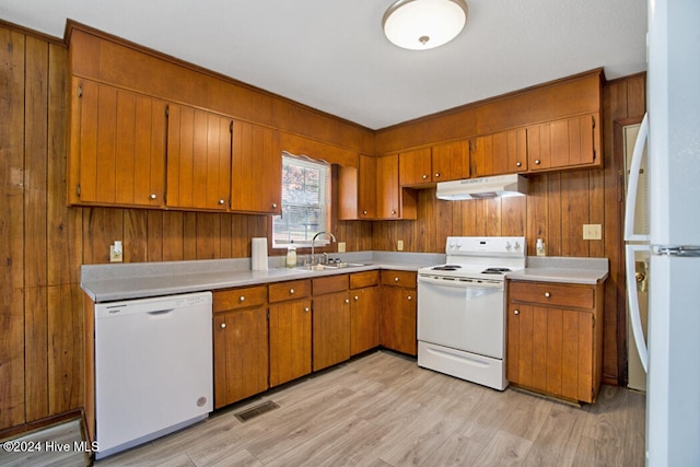 kitchen featuring wooden walls, white appliances, sink, and light hardwood / wood-style flooring