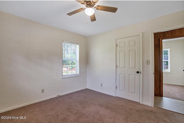 carpeted empty room featuring a wealth of natural light and ceiling fan