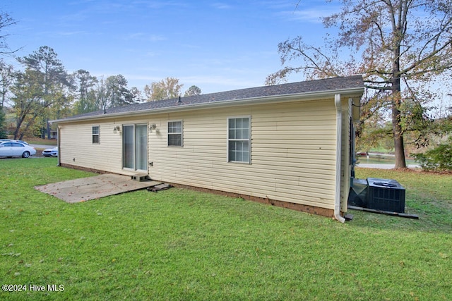 back of house with central AC unit and a lawn