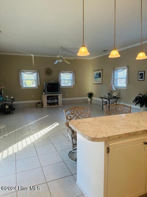 kitchen featuring pendant lighting, a kitchen bar, light tile patterned floors, and crown molding