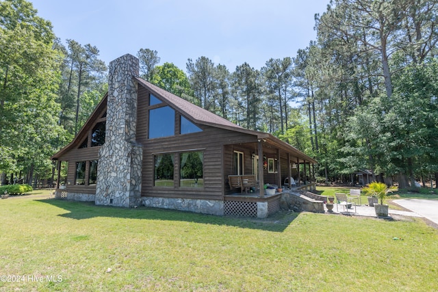 view of side of home featuring covered porch and a yard