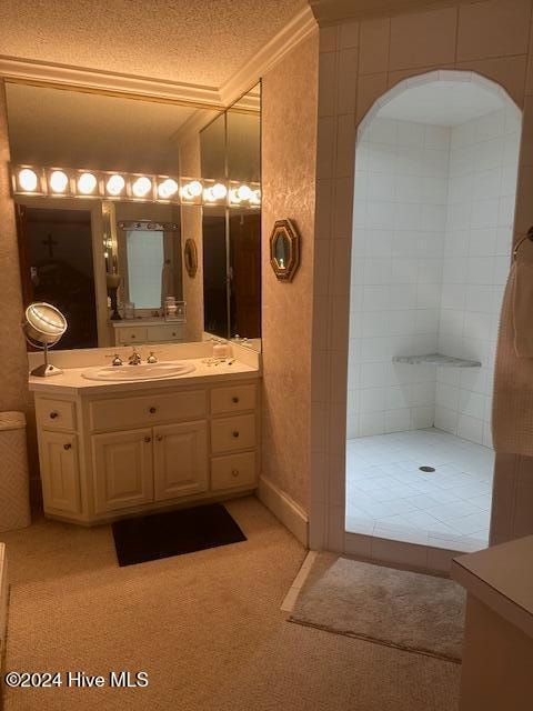 bathroom featuring a shower, vanity, a textured ceiling, and crown molding