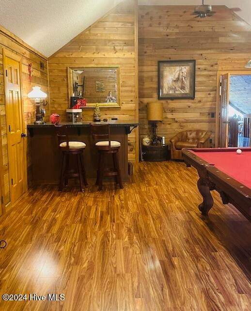 bar featuring pool table, hardwood / wood-style floors, lofted ceiling, and wood walls