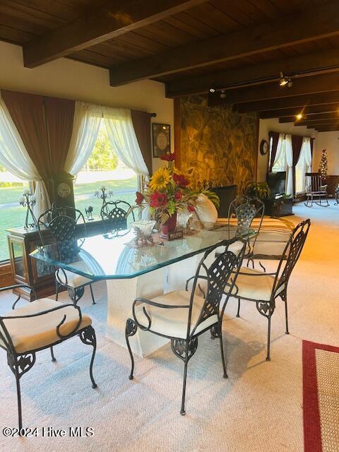 carpeted dining area with wooden ceiling, beamed ceiling, and a water view