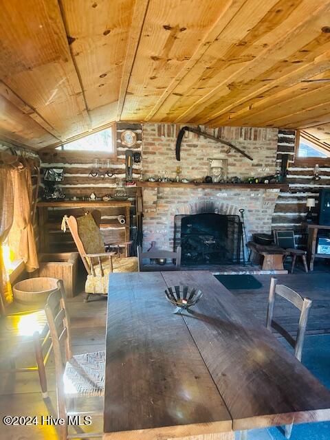 unfurnished dining area with a brick fireplace, a wealth of natural light, lofted ceiling, and wooden ceiling