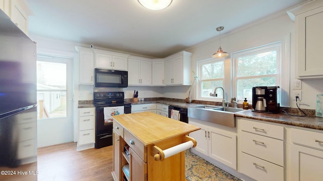 kitchen featuring sink, black appliances, white cabinets, light hardwood / wood-style floors, and hanging light fixtures